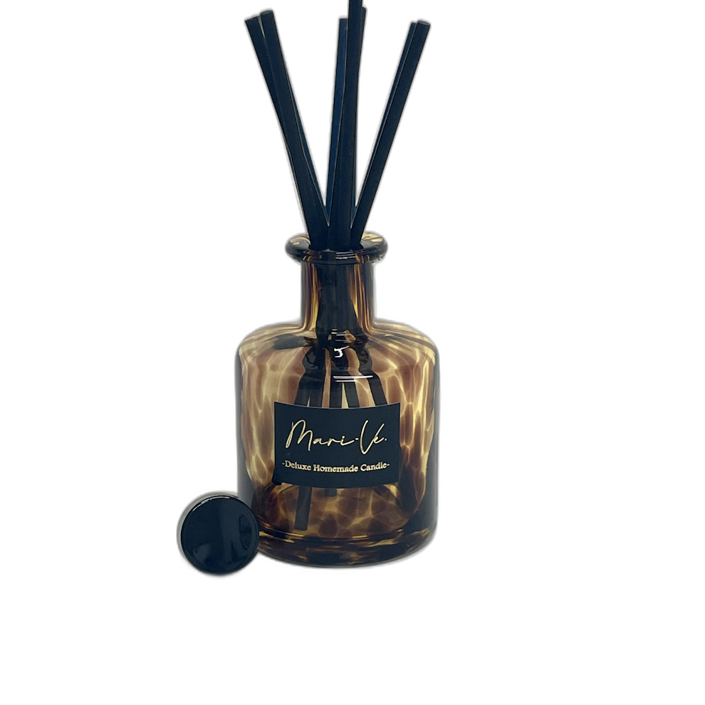 Mari-Ve geurdiffuser in bruin wildprint glas met zwarte stokjes en losse dop – luxe huisparfum op transparante achtergrond