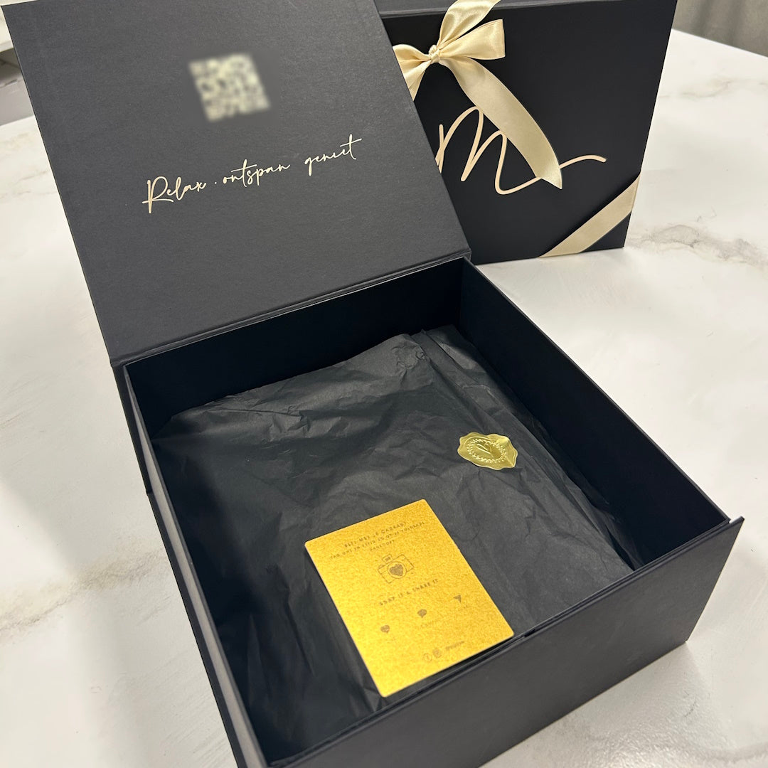 Open zwarte Mari-Ve geschenkdoos met gouden lint en quote “Relax. Ontspan. Geniet” – luxe cadeauverpakking met zwarte zijdepapier en goudkleurige kaart