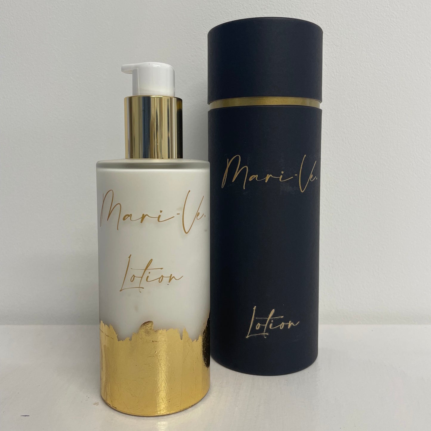Mari-Ve - Zwarte koker met gouden opdruk logo en lotion met melkachtig glazen roomspray fles met gouden opdruk logo en lotion