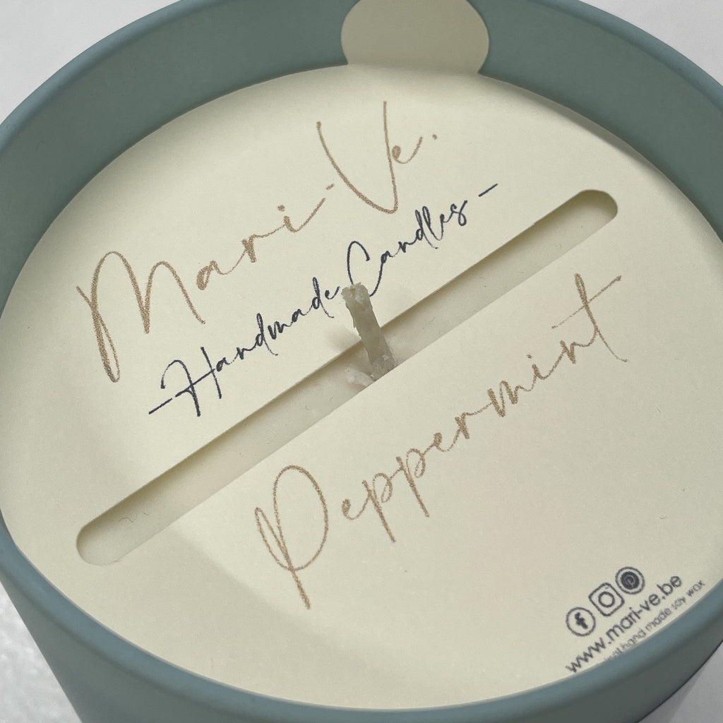 Detail van Mari-Ve’s kaarsstofdoek met handgeschreven logo, Peppermint-geur en handig lipje om het doekje makkelijk met de vingers te verwijderen. 