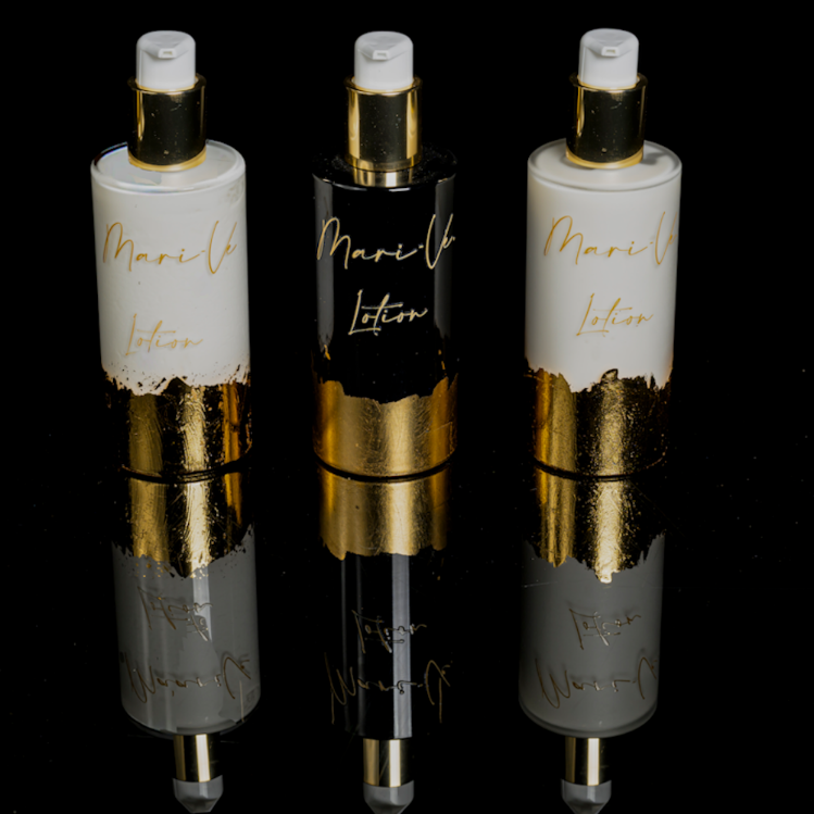 Drie luxe lotionflacons uit de Mari-Ve collectie, met een stijlvolle afwerking in wit, zwart en glanzend goud, gepresenteerd op een reflecterend zwart oppervlak voor een premium uitstraling.